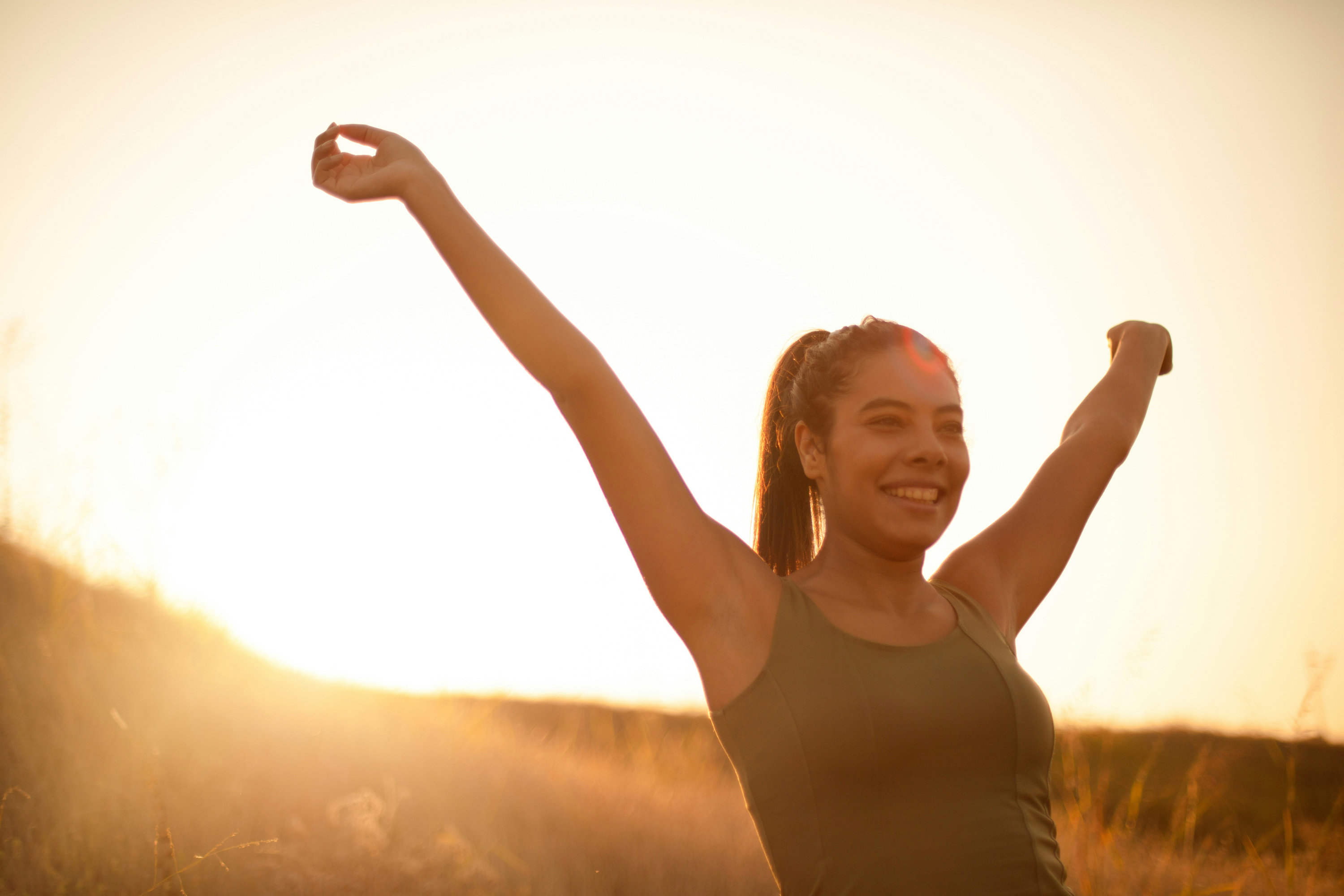 Woman celebrating with arms raised at sunset